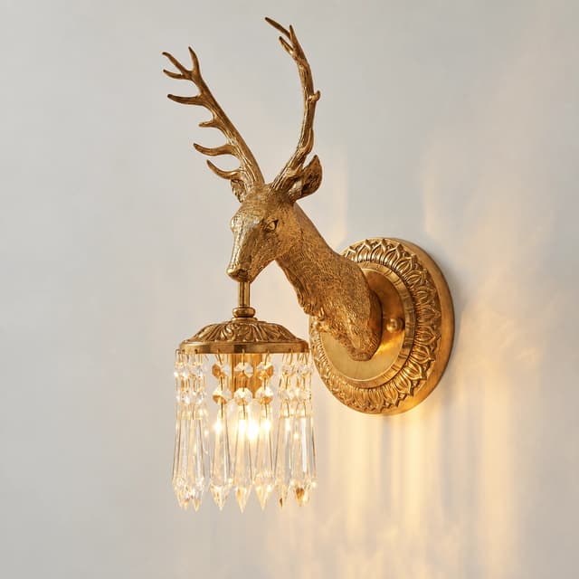 Close up of an antique gold copper deer head wall sconce with detailed antlers and textured sculptural metalwork