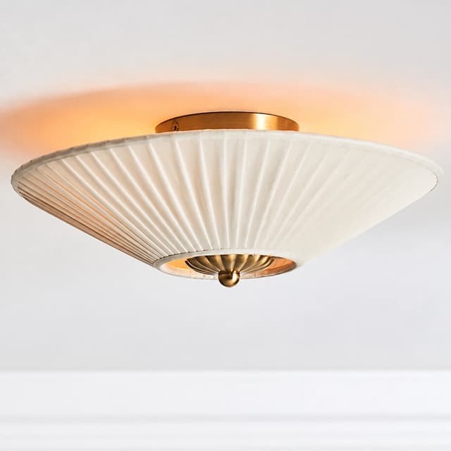 Copper finish Art Deco flush mount ceiling light with a softly glowing ivory pleated fabric shade