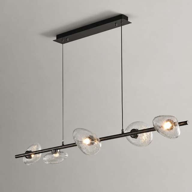 Six light linear chandelier with clear textured glass shades over a contemporary kitchen island and dining table