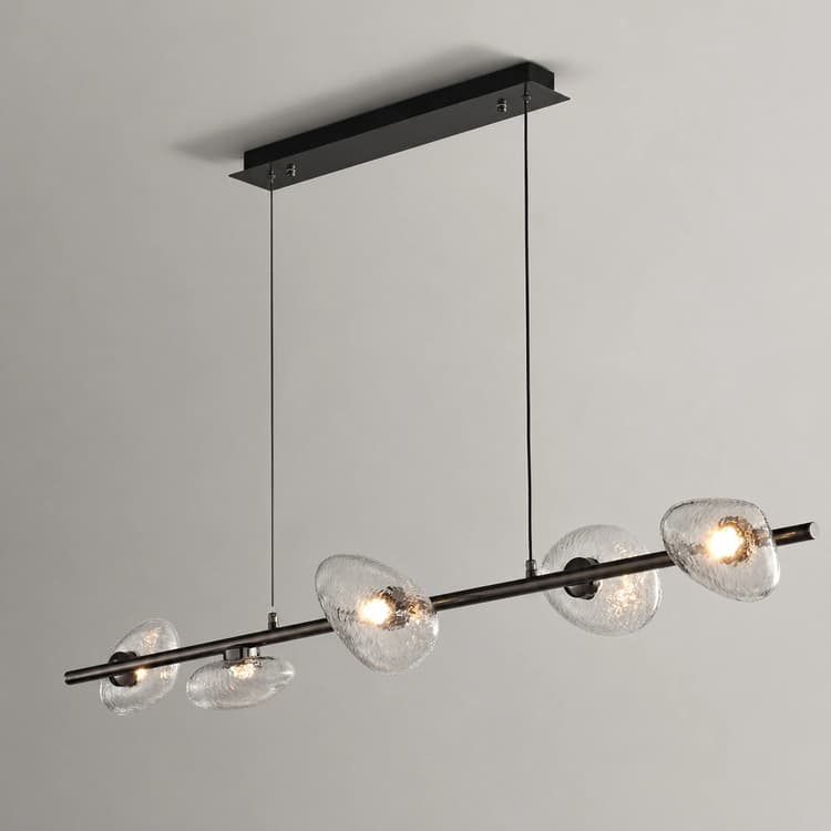 Six light linear chandelier with clear textured glass shades over a contemporary kitchen island and dining table