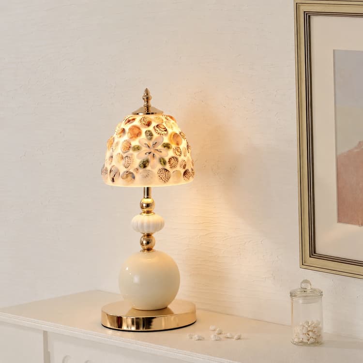 Seashell table lamp with a domed shell and glass shade, ivory ceramic base, and polished gold metal accents