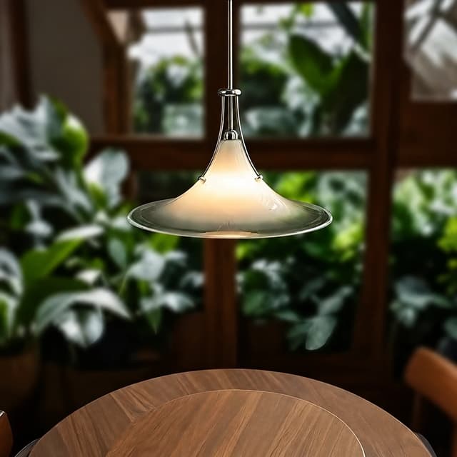Frosted glass saucer pendant light with a clear rim, polished metal frame and warm glow above a round dining table