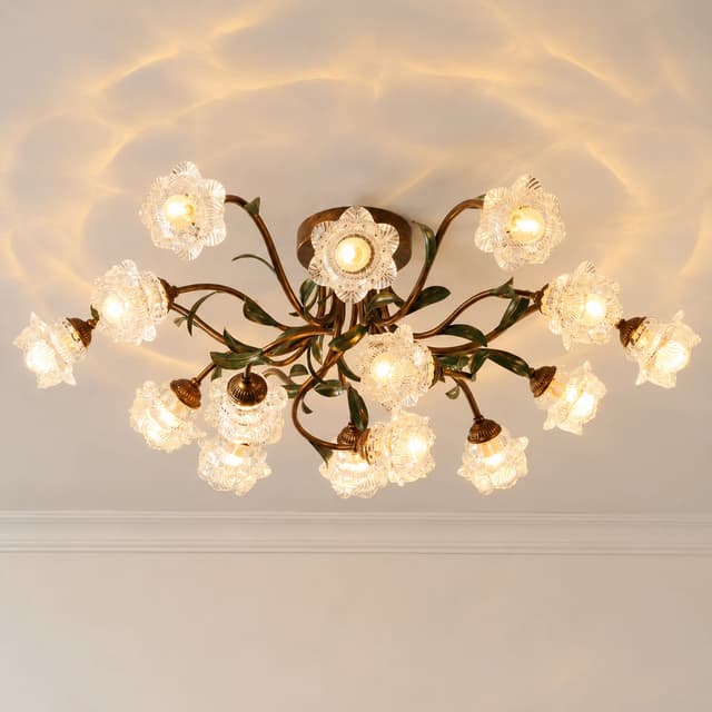 Vintage floral ceiling light with creamy white flower shaped shades, bronze metal arms, and green botanical details