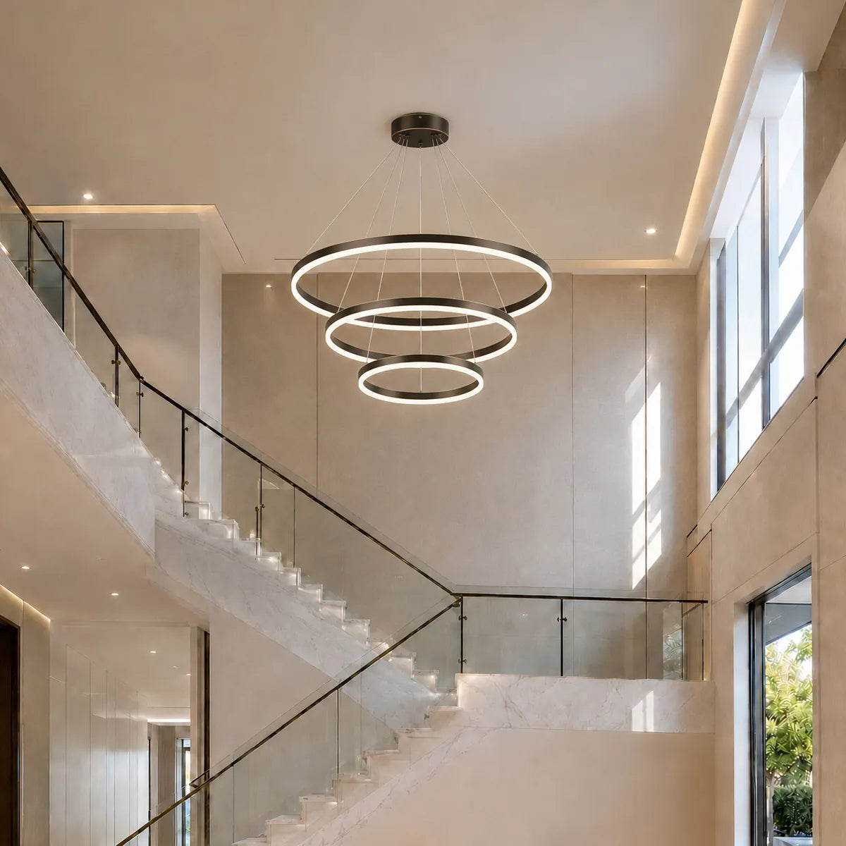Large circular LED chandelier installed in a bright stairwell foyer with adjustable cables