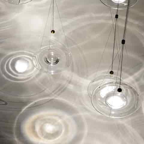 Clear glass disc pendant lights creating water ripple light patterns across the ceiling with delicate cable suspension