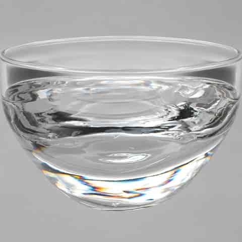 Close up of clear glass disc pendant shade showing thick optical glass, curved lens form and rainbow like light refraction