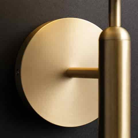 Close up of brushed brass wall plate and arm detail on a globe wall sconce