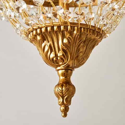Detailed view of an ornate antique gold crystal chandelier with layered clear crystals and amber teardrops
