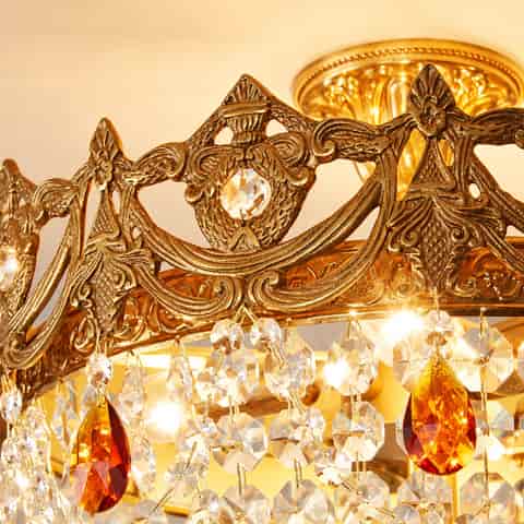 Antique gold crystal flush mount chandelier illuminated with warm light and amber crystal accents