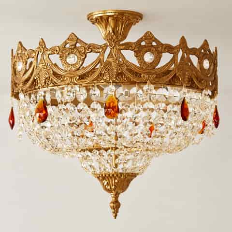 Close up of layered faceted crystal strands and ornate gold decorative finial on a vintage chandelier