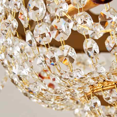 Close up of faceted amber teardrop crystal and clear crystal strands on an ornate gold chandelier