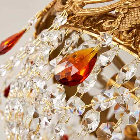 Close up of ornate antique gold metalwork and faceted crystal details on a luxury chandelier