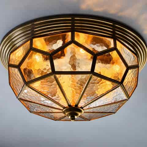 Close up of textured amber stained glass panels and dark bronze geometric framing on a Tiffany style ceiling light