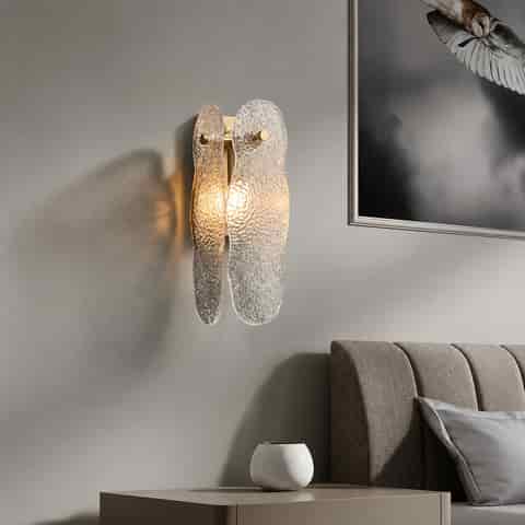 Textured glass wall sconce beside a modern bedroom bed with warm ambient lighting