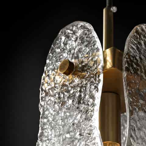 Detailed view of hammered textured glass and brass hardware on a modern wall sconce