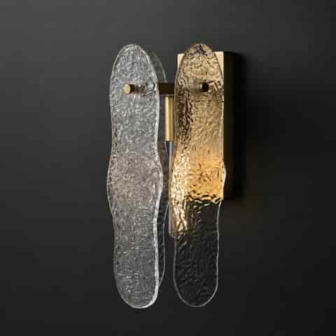 Layered organic textured glass wall sconce with warm brass finish in a modern living room