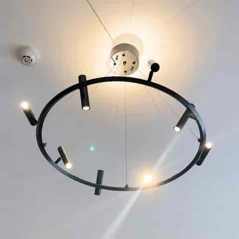 Bottom view of modern black ring spotlight chandelier with multiple directional light heads and cable suspension