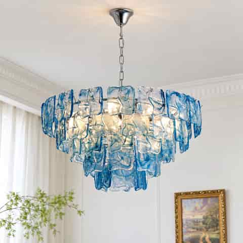 Blue glass chandelier installed beneath a decorative ceiling medallion in a bright interior
