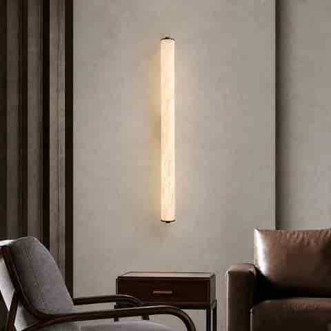 Slim vertical cylinder wall sconce glowing in a modern living room seating area