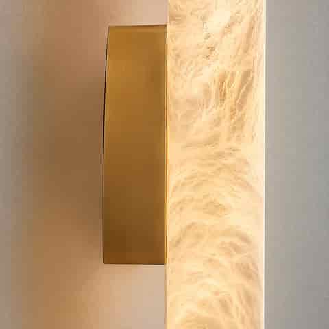 Close up of brass wall plate and illuminated marble veined cylinder diffuser