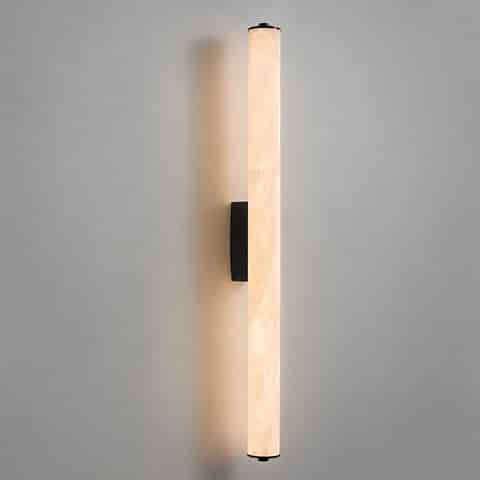 Long vertical alabaster style wall sconce with warm glow and black metal mounting plate