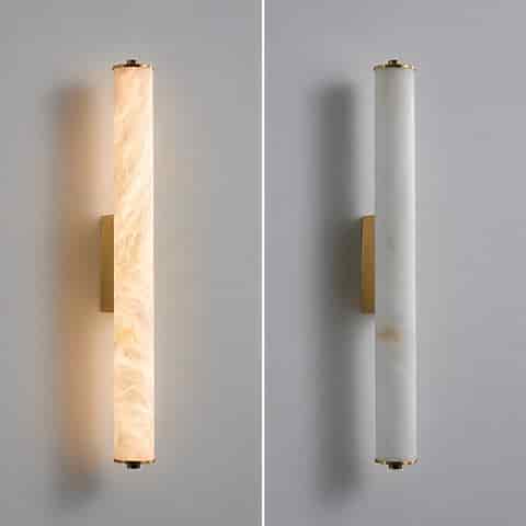 Brass cylinder wall sconce shown illuminated and unlit with translucent stone texture