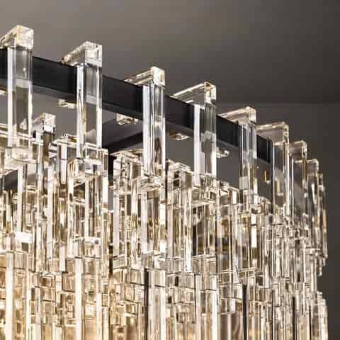 A close up of a black metal and crystal chandelier, featuring cascading clear crystal accents and warm lighting