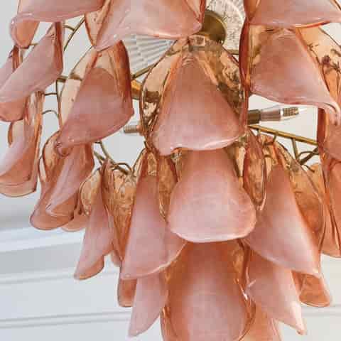 Close up of pink glass petal shades and metal supports on a decorative chandelier