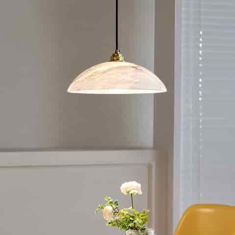 Natural alabaster pendant light with brass tone hardware in a bright contemporary dining space
