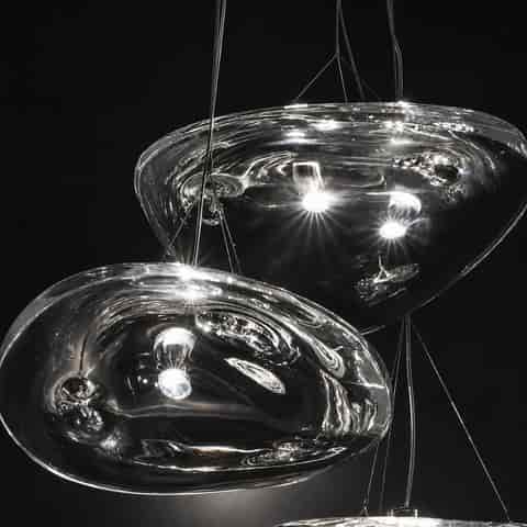 Close up of clear sculptural glass pendant shades showing thick fluid edges, rippled texture and polished metal details