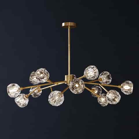 Large gold branch chandelier with multiple faceted clear globe shades on a dark background