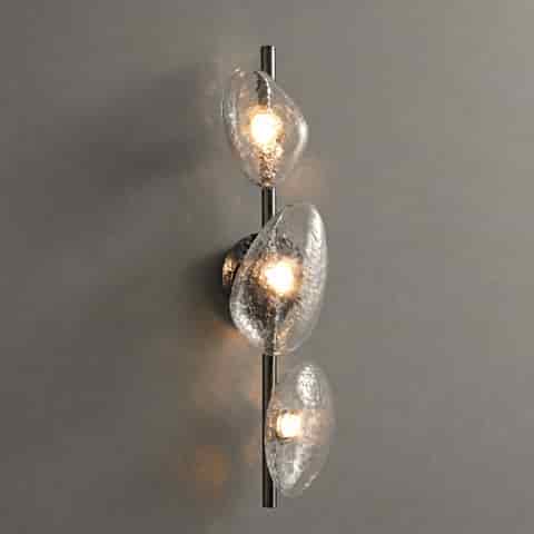Three light clear textured glass wall sconce with organic pebble shades and warm illumination