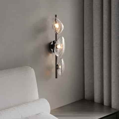 Three light textured clear glass wall sconce used as a sculptural accent light in a modern interior