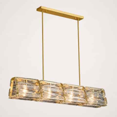 Gold copper and clear textured glass linear chandelier glowing warmly against a dark background 100cm