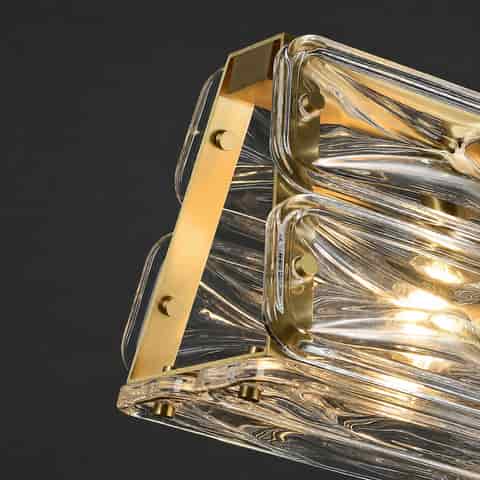 Side detail of gold copper frame and layered clear textured glass blocks on a modern linear chandelier
