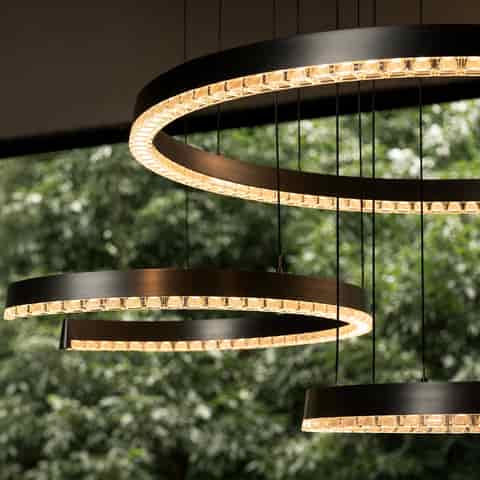 Illuminated graphite gray spiral LED pendant lights in multiple sizes with warm glow and sculptural curved forms