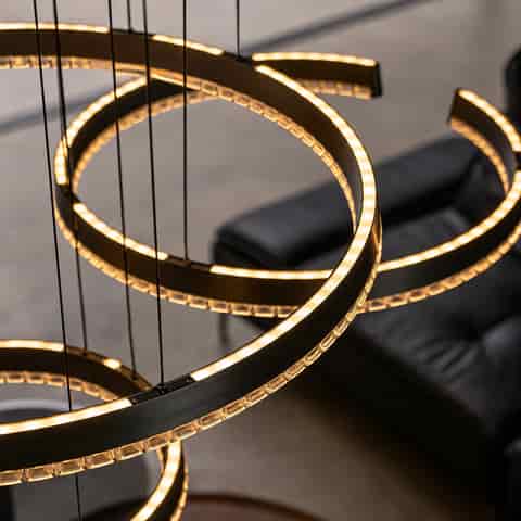 Close up of illuminated graphite gray spiral chandelier showing warm LED light through the faceted clear diffuser