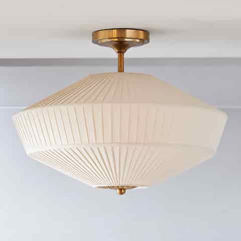 French Art Deco copper finish drum ceiling light with geometric pleated fabric shade in a warm contemporary interior