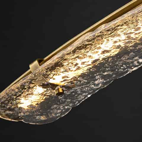 Close up of thick water textured glass diffuser and brass wall light frame