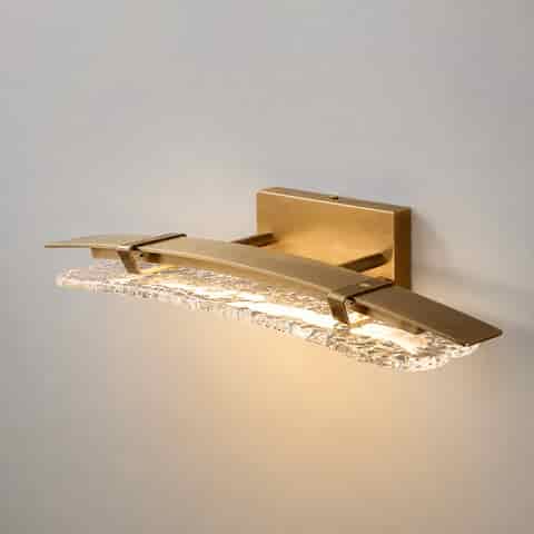 Brass textured glass wall sconce with curved linear frame and warm ambient lighting