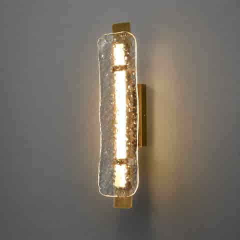 Modern vertical brass wall sconce with illuminated textured clear glass panel