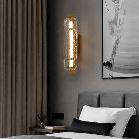 Vertical textured glass wall sconce installed beside a modern bedroom bed