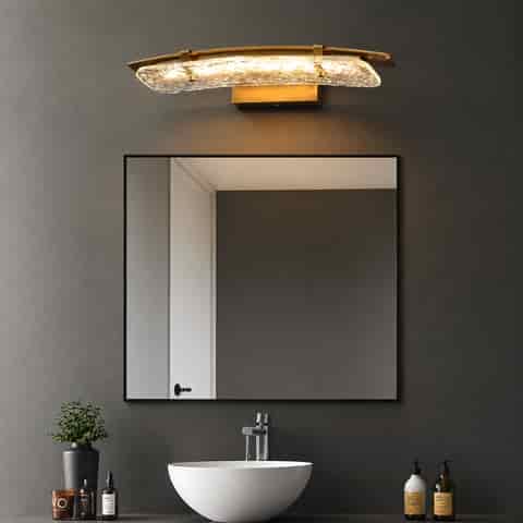 Horizontal brass and textured glass vanity light above a bathroom mirror