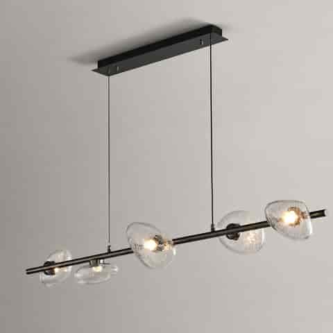 Six light linear chandelier with clear textured glass shades over a contemporary kitchen island and dining table