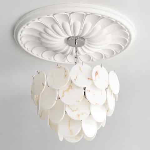 Front detail of layered faux marble chandelier with white round discs, amber veining and cascading sculptural form