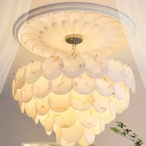 Illuminated faux alabaster chandelier with layered marble look discs creating a soft warm ambient glow