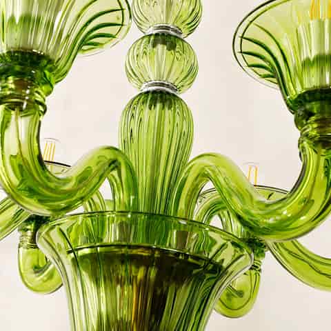 Close up of green glass chandelier center column and sculpted curved arms