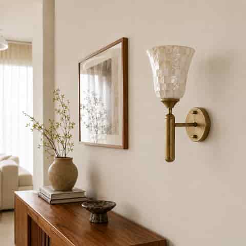 Pearlescent shell mosaic wall sconce with antique brass frame in a bright neutral interior