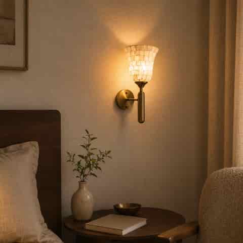 Antique brass shell mosaic wall sconce glowing beside a cozy bedroom reading corner