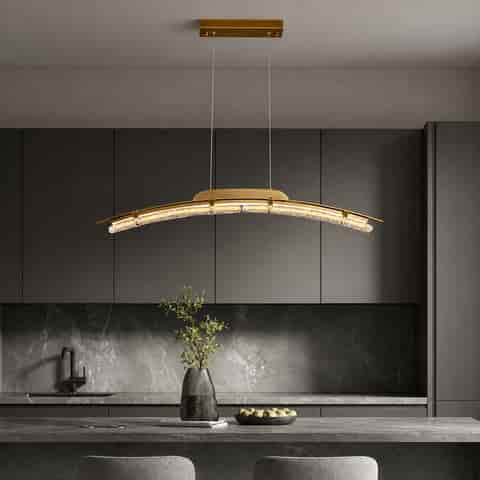 Curved copper and textured glass linear chandelier with warm illumination suspended above a modern kitchen island